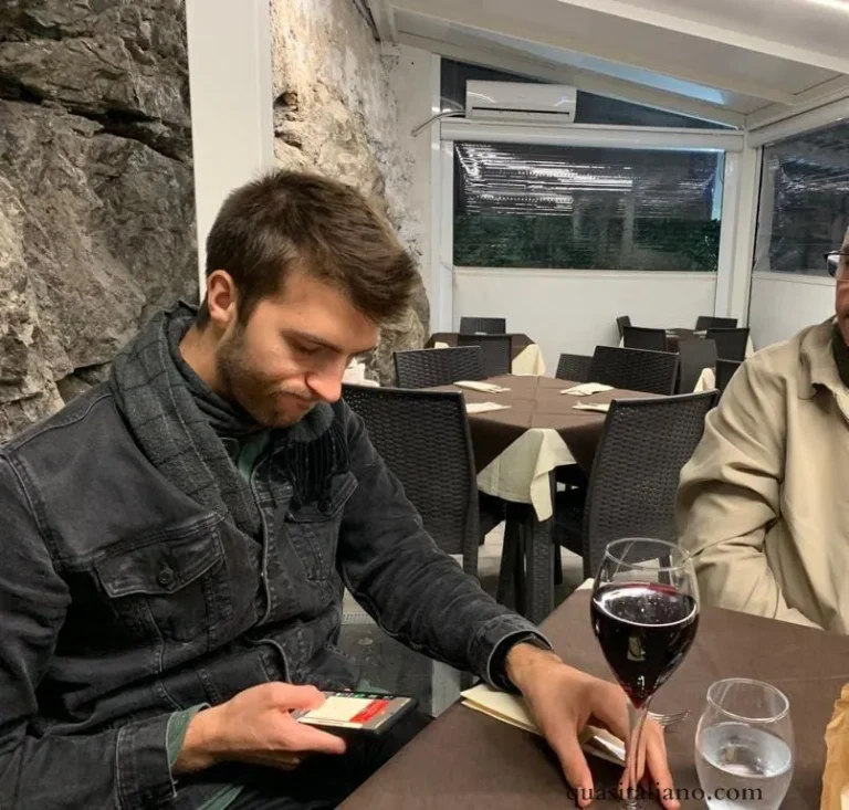 picture of a guy at a table looking at his phone with a slightly frustrated expression