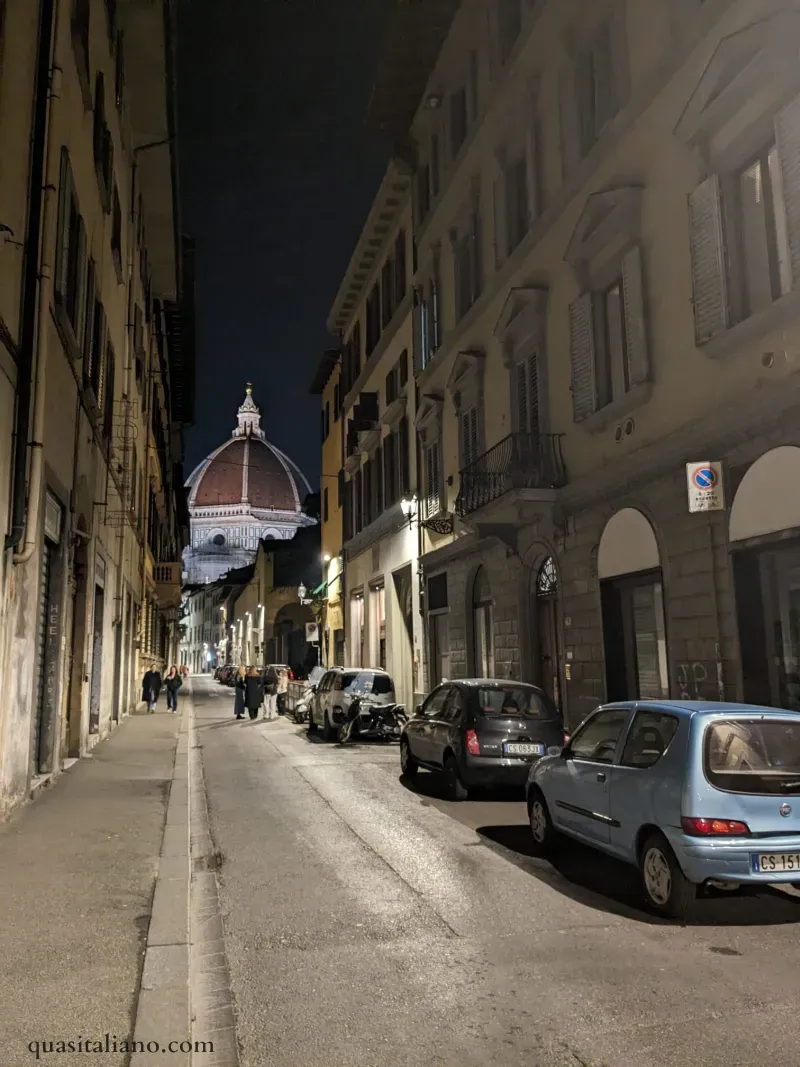 parallel parked cars on a street at night in Florence
