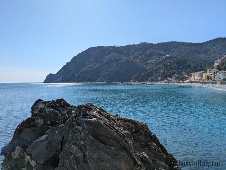 View of Monterosso al Mare beachfront and cliffs along the Ligurian Sea in Cinque Terre, Italy, on a clear sunny day