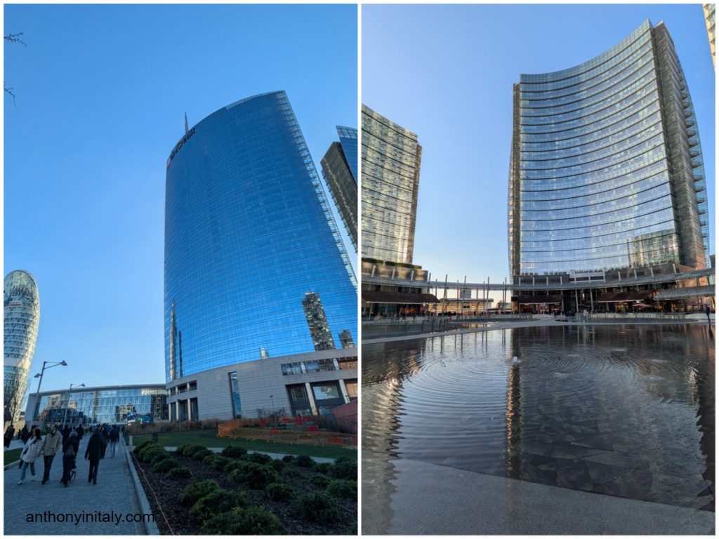 Modern glass skyscrapers at Piazza Gae Aulenti in Milan's Porta Nuova district, reflected in a still reflecting pool on a clear blue-sky day.