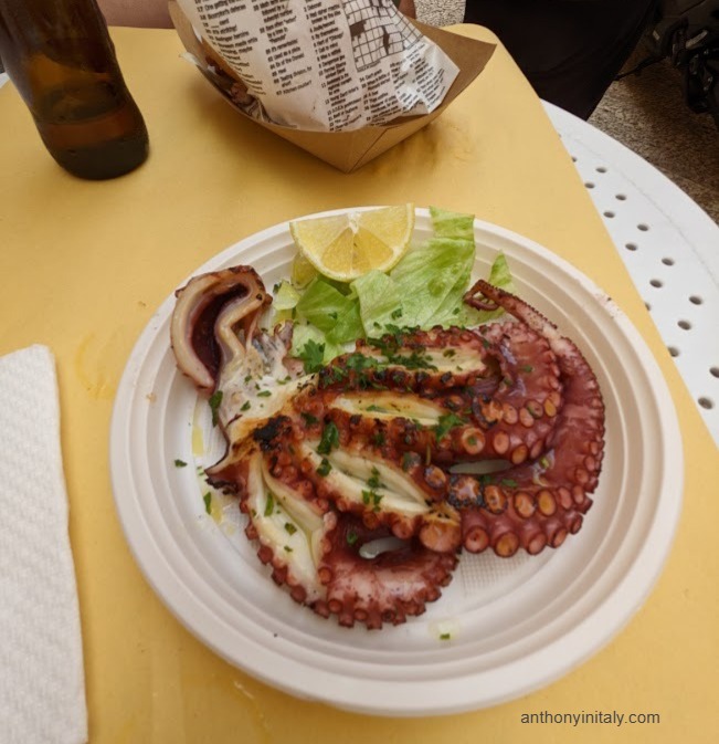Grilled octopus on a plastic plate with lemon and lettuce at Frisc & Mang in Bari, Puglia.