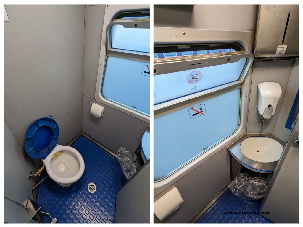 Interior of an Italian regional train bathroom showing a blue toilet on the left and a small corner sink with soap dispenser on the right, photographed by Anthony in Italy