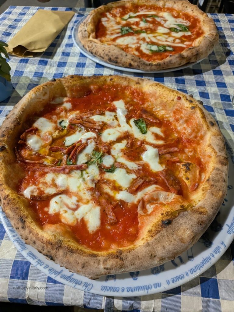 Two Neapolitan-style pizzas at Fratelli Coppola in Milan — one margherita, one with salumi — on a blue checkered tablecloth