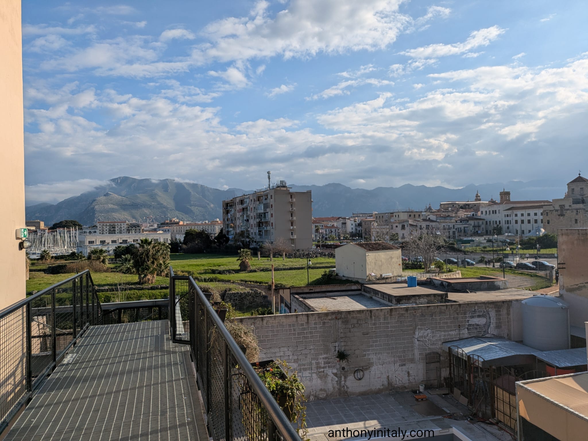 Rooftop terrace at Ostello Bello Palermo with views of the city, marina, and mountains in the background.